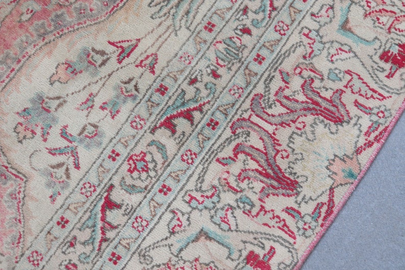 Puede incluir: Una alfombra vintage con fondo crema y intrincados patrones florales en tonos rosa, rojo y azul.