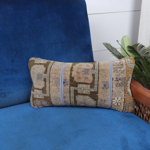 May include: A blue velvet armchair with a decorative pillow featuring a traditional Turkish kilim pattern in shades of brown, beige, and blue.