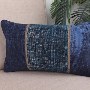 May include: Rectangular decorative pillow with a dark blue and teal color scheme. The pillow features a central teal panel with a textured pattern, framed by vertical brown stripes and flanked by solid dark blue sections.