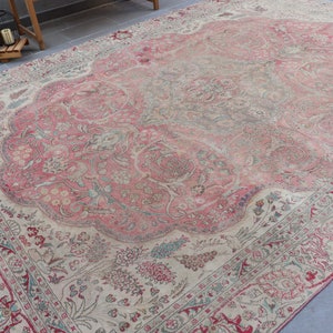 Puede incluir: Una alfombra vintage con un esquema de color rosa y crema. La alfombra tiene un patr&oacute;n floral con detalles intrincados. La alfombra est&aacute; desgastada y descolorida, lo que le da un car&aacute;cter &uacute;nico.