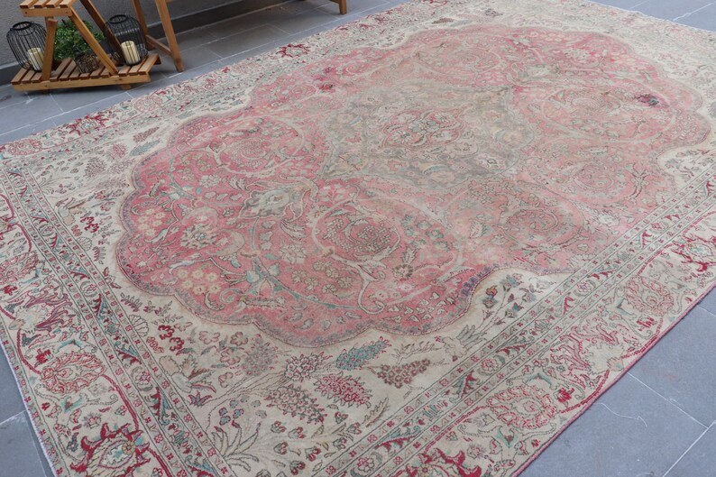 Puede incluir: Una alfombra vintage con un esquema de color rosa y crema. La alfombra tiene un patr&oacute;n floral con detalles intrincados. La alfombra est&aacute; desgastada y descolorida, lo que le da un car&aacute;cter &uacute;nico.