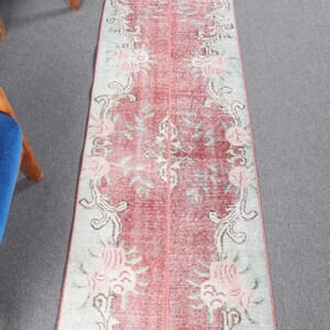 Könnte beinhalten: Ein Vintage-Läufer mit einem floralen Muster in Rosa-, Weiß- und Grautönen. Der Teppich hat einen Used-Look und ist perfekt, um jedem Raum einen Hauch von Vintage-Charme zu verleihen.