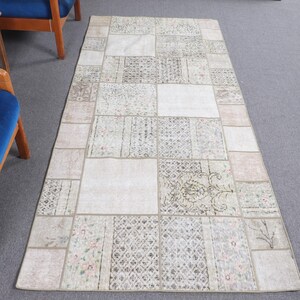 Puede incluir: Una alfombra de patchwork blanco y beige con un patrón floral. La alfombra está hecha de diferentes piezas de tela cosidas juntas.