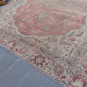 Puede incluir: Una alfombra vintage con fondo crema y un gran dise&ntilde;o floral rosa en el centro. La alfombra tiene un borde detallado con motivos florales rojos, verdes y azules.