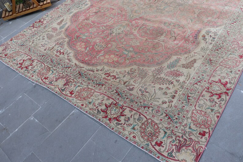 Puede incluir: Una alfombra vintage con fondo crema y un gran dise&ntilde;o floral rosa en el centro. La alfombra tiene un borde detallado con motivos florales rojos, verdes y azules.