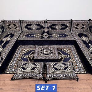 May include: A modular floor seating set featuring dark blue velvet cushions with intricate white and black geometric patterns. The set includes long back cushions, corner pieces, a central square floor cushion, two rectangular pillows, and a rug.
