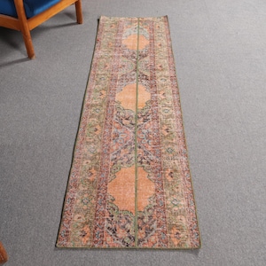 Puede incluir: Una alfombra larga y rectangular con un diseño persa tradicional. La alfombra tiene un fondo naranja claro con intrincados patrones florales en tonos de verde, azul y rojo.