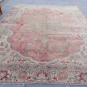 Puede incluir: Una alfombra vintage con fondo crema y un gran dise&ntilde;o floral intrincado en tonos de rosa, rojo y verde. La alfombra tiene un aspecto descolorido y desgastado, lo que le da un car&aacute;cter &uacute;nico.