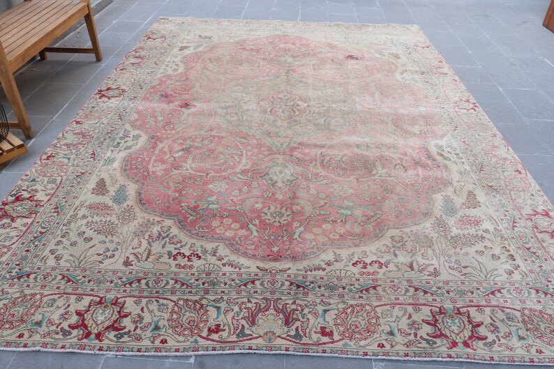 Puede incluir: Una alfombra vintage con fondo crema y un gran dise&ntilde;o floral intrincado en tonos de rosa, rojo y verde. La alfombra tiene un aspecto descolorido y desgastado, lo que le da un car&aacute;cter &uacute;nico.