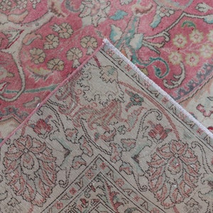 Puede incluir: Primer plano de una alfombra de color rosa y crema con flecos. La alfombra tiene un dise&ntilde;o floral con detalles intrincados.