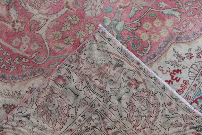 Puede incluir: Primer plano de una alfombra de color rosa y crema con flecos. La alfombra tiene un dise&ntilde;o floral con detalles intrincados.