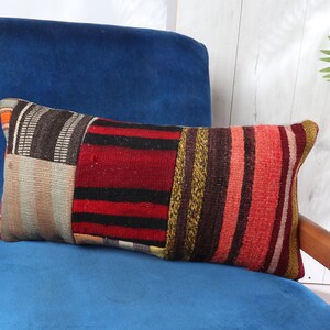 May include: A colorful striped throw pillow with a patchwork design. The pillow is made of woven fabric and has a variety of colors, including red, orange, yellow, green, blue, and purple.