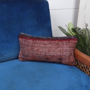 Puede incluir: Un cojín de color rojo y marrón con estampado sobre un sofá de terciopelo azul.
