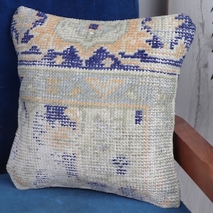 May include: A square throw pillow with a woven pattern in shades of blue, beige, and white. The pillow is made of a soft, textured fabric and has a subtle geometric design.