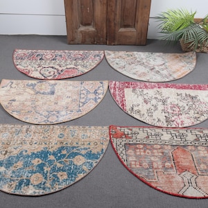 Könnte beinhalten: Sechs halbkreisförmige Teppiche mit verblichenen Mustern in Rot-, Blau- und Beigetönen. Die Teppiche sind auf einer grauen Oberfläche ausgestellt und unterstreichen ihre Vintage-Designs. Diese Teppiche werden wahrscheinlich als dekorative Bodenbeläge verwendet.