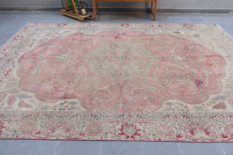 Puede incluir: Una alfombra vintage con un esquema de color rosa y crema. La alfombra tiene un patr&oacute;n floral con intrincados detalles. La alfombra est&aacute; en buen estado y tiene un aspecto desgastado.
