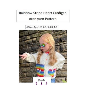 May include: A white cardigan with a rainbow heart design. The cardigan is knitted with a textured aran stitch. The cardigan is available in four sizes for ages 1-2, 2-3, 3-4, and 4-5. The text "Hearts & Coronets" is printed on the bottom of the image.