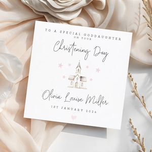 May include: A square white greeting card with black text reading TO A SPECIAL GODDAUGHTER ON YOUR Christening Day, Olivia Louise Miller, and 1ST JANUARY 2026. The design features a small watercolour church illustration surrounded by light pink stars.