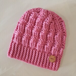 May include: Pink crocheted beanie with a brown leather tag that says "Stitches by Bri"