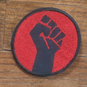 Parche bordado Puño de Resistencia en lona roja sobre negra para protestar contra la resistencia radical