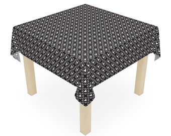 May include: Black and white tablecloth with a repeating pattern of a stylized Mickey Mouse head in a heart shape. The tablecloth is draped over a square wooden table with four legs.