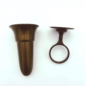 May include: A brown ceramic vase with a flared top and a round base. The vase is designed to hold a single flower or stem. It comes with a separate metal ring that can be used to hold the vase in place.