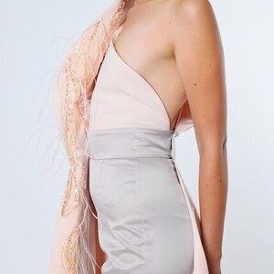 May include: A one-shoulder dress with a pink and gray color scheme. The dress has a feather trim and a fitted silhouette.