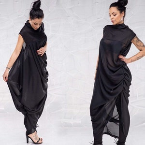 May include: A black, draped, sleeveless dress with a high neckline. The dress is made of a sheer fabric and has a flowing, asymmetrical design.
