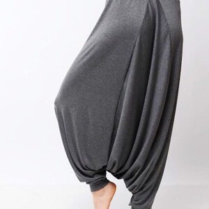 May include: Gray, loose-fitting pants with a wide leg and a gathered, draped design. The pants are made of a soft, stretchy fabric.