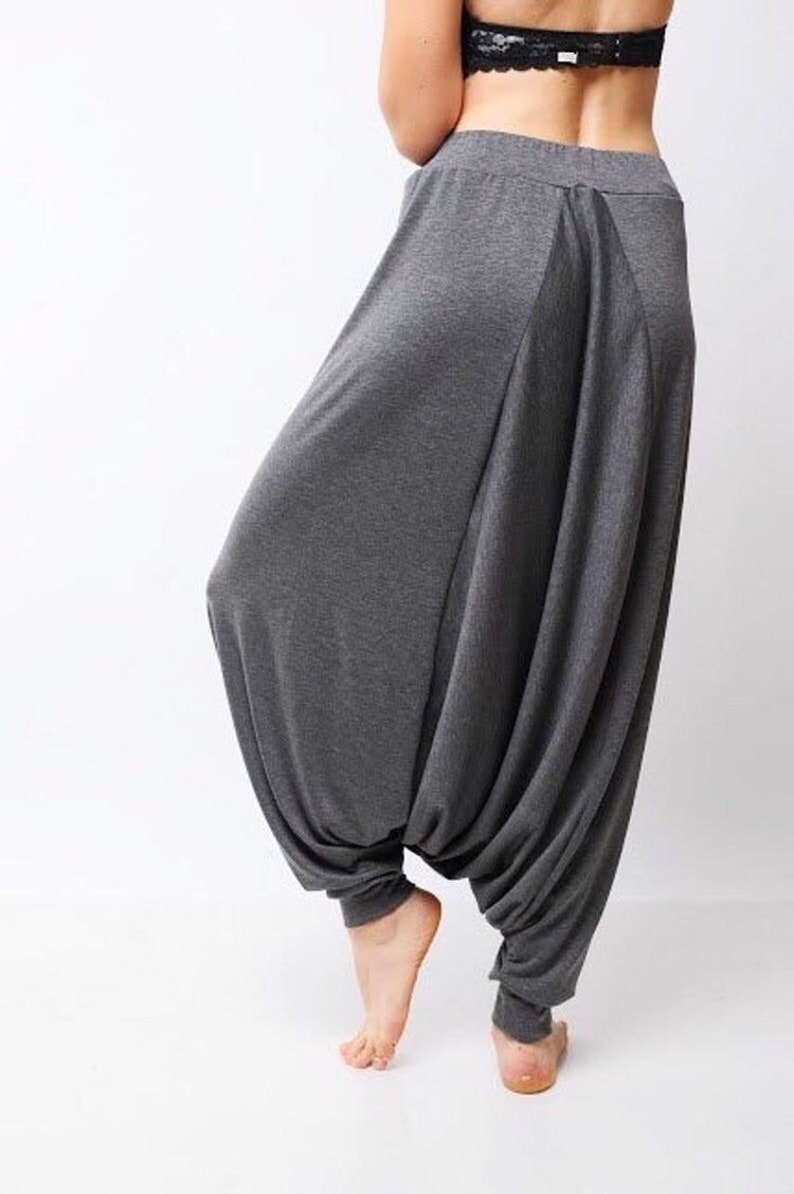 May include: Gray, loose-fitting pants with a wide leg and a gathered, draped design. The pants are made of a soft, stretchy fabric.