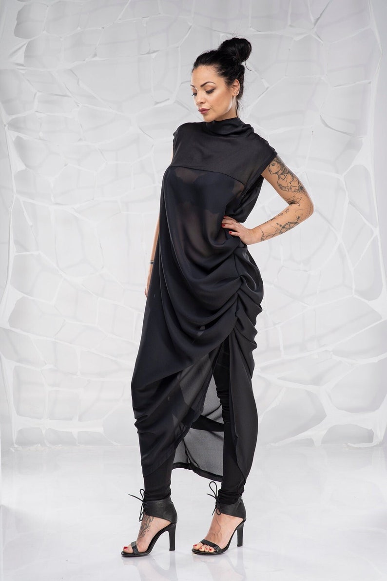 May include: A black sheer dress with a gathered skirt and a high neckline. The dress is worn with black leggings and black heeled sandals.