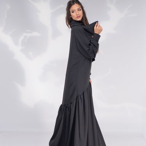 May include: A black long-sleeved dress with a ruffled hem. The dress has a high neckline and a relaxed fit.