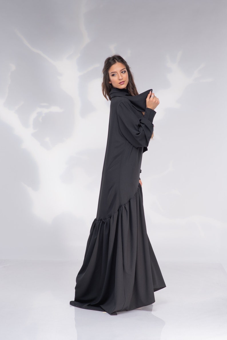 May include: A black long-sleeved dress with a ruffled hem. The dress has a high neckline and a relaxed fit.
