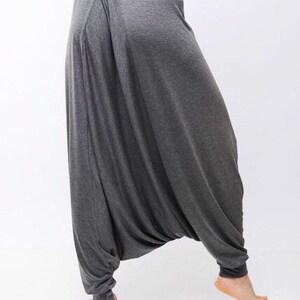 May include: Gray, loose-fitting pants with a wide leg and a gathered waist. The pants are made of a soft, stretchy fabric.