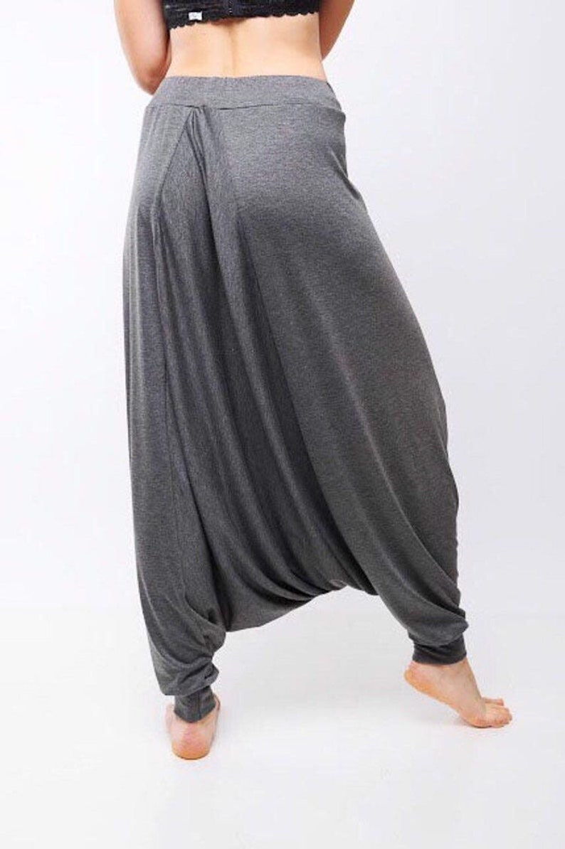 May include: Gray, loose-fitting pants with a wide leg and a gathered waist. The pants are made of a soft, stretchy fabric.
