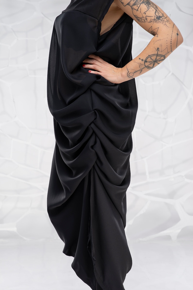 May include: A black, flowing, draped dress with a gathered, asymmetrical hemline.