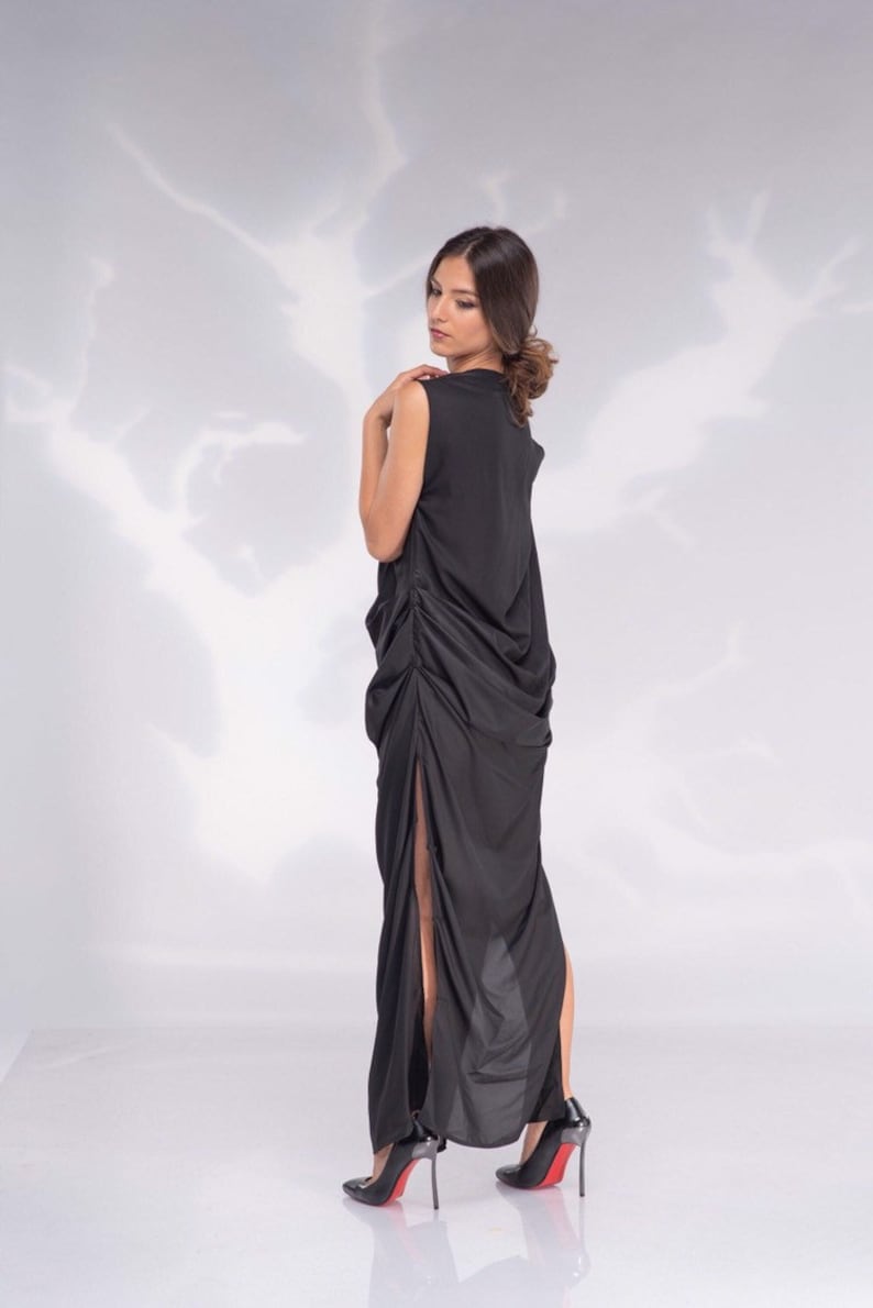 May include: A sleeveless black dress with a high neckline and a draped, asymmetrical design. The dress features a high slit on one side and is paired with black high heels with red soles.