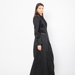 May include: A long black coat with a zipper closure and silver accents. The coat has a fitted bodice and a flowing skirt.