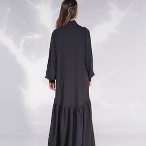 May include: A black long-sleeved dress with a high neck and a ruffled hem.