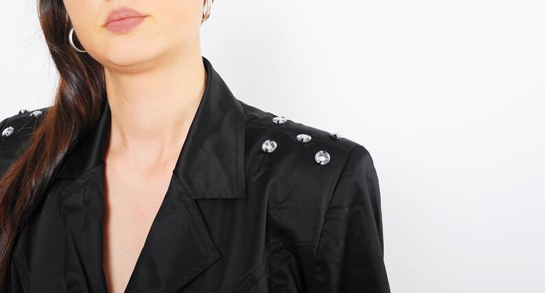 May include: A black blazer with a v-neck collar and silver rhinestones on the shoulder.