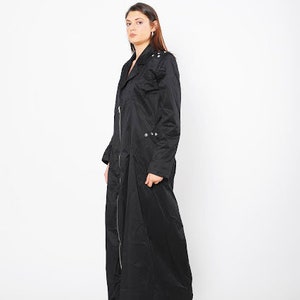 May include: A long black coat with a zipper closure and silver accents. The coat has a collar and long sleeves.