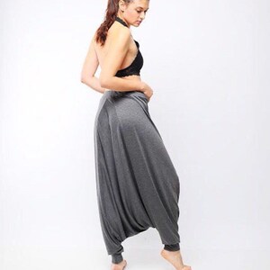 May include: A woman wearing a gray pair of harem pants with a black lace halter top.