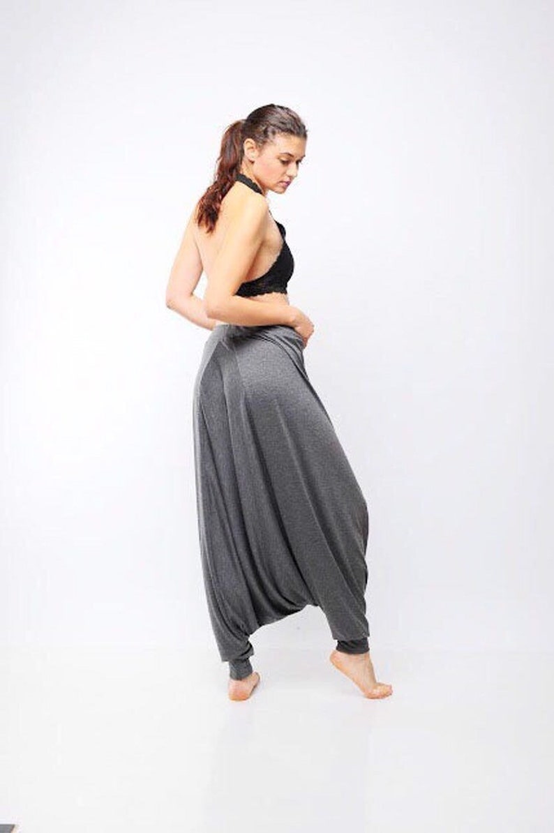 May include: A woman wearing a gray pair of harem pants with a black lace halter top.