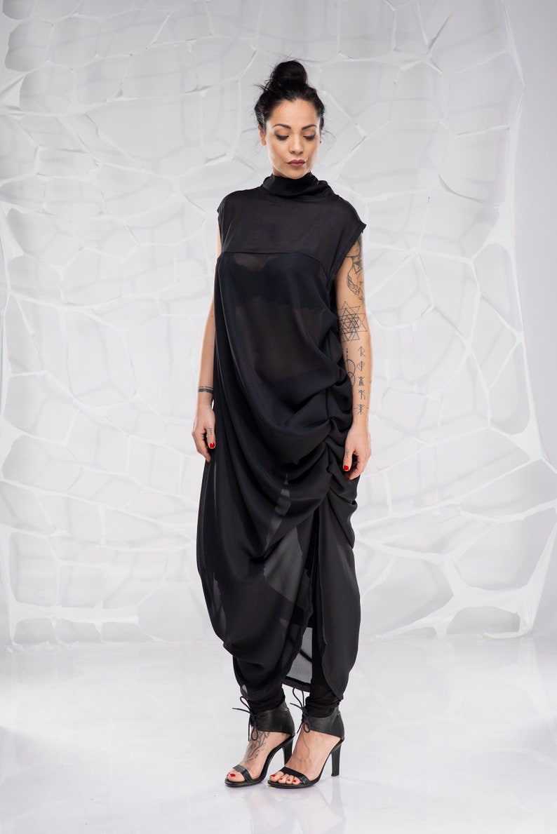 May include: A black, loose-fitting, sleeveless dress with a high neck and a gathered design. The dress is made of a sheer fabric and is worn with black heeled sandals.