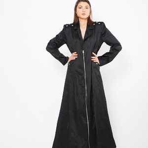 May include: A long black coat with a zipper closure and a stand-up collar. The coat has a slightly flared silhouette and is made of a smooth, lightweight fabric.