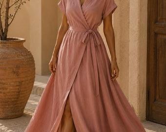 Pode incluir: Um vestido envelope rosa seco com mangas curtas, decote em V e um cinto de tecido a combinar na cintura. A saia comprida até ao chão tem uma abertura frontal e a peça é feita de um tecido texturizado com um padrão de trama visível.