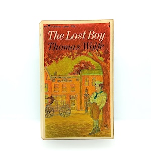 May include: Vintage paperback book titled "The Lost Boy" by Thomas Wolfe. The cover art features a colorful illustration of a young man leaning against a tree, with a town and horse-drawn carriage in the background. The book is from the Perennial Library.