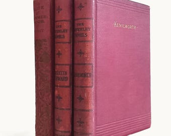 Op de afbeelding: Drie vintage hardcover boeken met donkerrode stoffen kaften. De ruggen zijn voorzien van goudkleurige letters en decoratieve motieven. De voorkant van het rechterboek toont de titel Kenilworth in gouden letters en horizontale reliëflijnen.