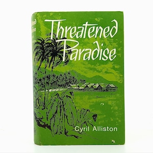 May include: A vintage paperback book titled "Threatened Paradise" by Cyril Alliston. The cover is green with white text and a tropical illustration featuring palm trees and huts over water.