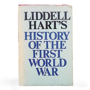 Puede incluir: Un libro antiguo titulado "Liddell Hart's History of the First World War". La portada es azul claro con texto negro y azul. El lomo es blanco y el borde superior es rojo.